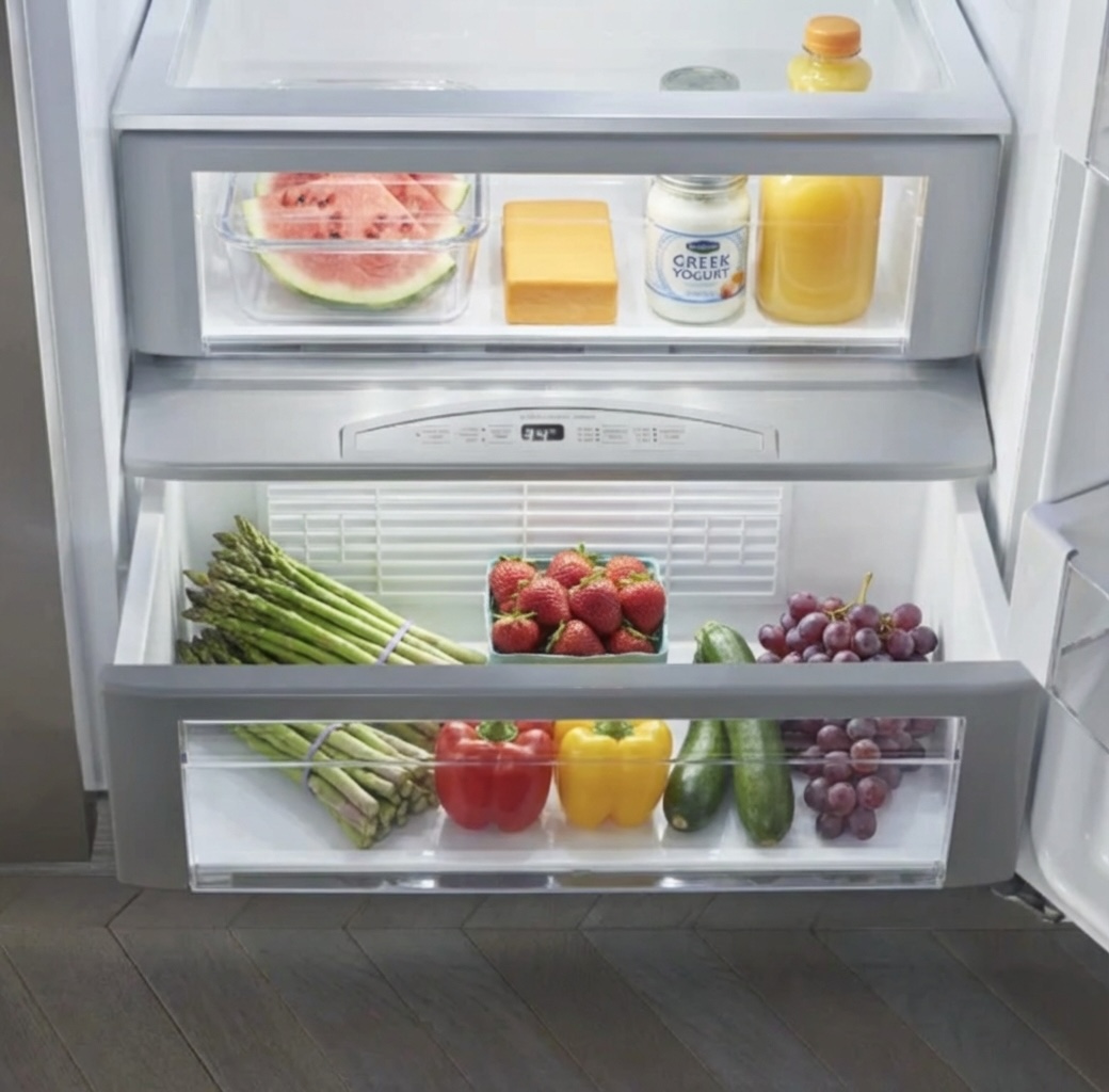 Open GE refrigerator crisper drawers stocked with fresh vegetables, cauliflower, eggplant, and produce